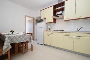 Il comprend une cuisine équipée d'une table et d'un réfrigérateur blanc. dans l'établissement Three-Bedroom Apartment Rabac near Sea, à Rabac