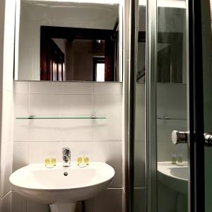 a white bathroom with a sink and a mirror at Noemi Old Town in Braşov +48 photos