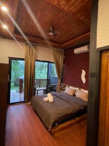a bedroom with a bed and a large window at Tetebatu Valley Bungalows in Tetebatu