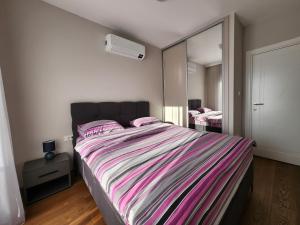 a bedroom with a large bed and a mirror at Green Apartments Podgorica With Garage in Podgorica