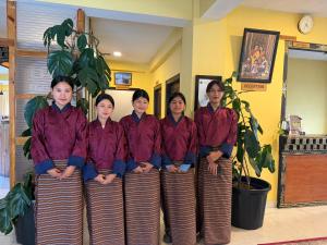 a group of women in purple shirts posing for a picture at Taktshang Paradise in Paro
