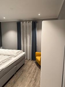 a bedroom with a bed and a yellow chair at Sokkelleilighet in Grindheim