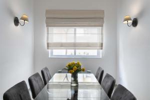 a dining room table with chairs and a vase of flowers at Four Bedroom Typical Maltese Townhouse - One Minute Away From The Seafront in Sliema