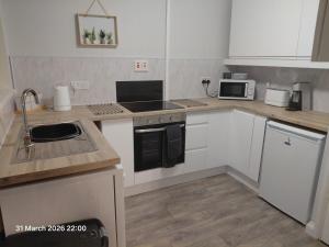 a kitchen with white cabinets and a stove top oven at Flat by the sea in Paignton