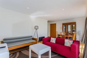 a living room with a red couch and a table at GuestReady - Santo Amaro apartment in Vila Franca do Campo