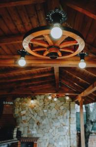 a wooden ceiling with a fan and a stone wall at къща за гости При Приятели in Nesebar