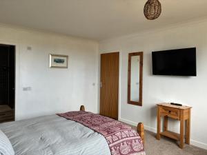 a bedroom with a bed and a television on the wall at Buttof Lewis B&B in Lionel
