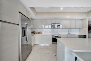 a kitchen with white cabinets and a stainless steel refrigerator at Beachwalk Resort in Hallandale Beach +68 photos