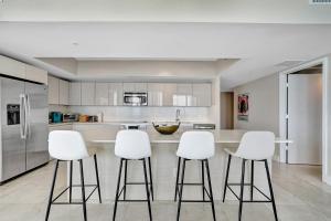 a kitchen with white bar stools and a counter at Beachwalk Resort in Hallandale Beach