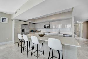 a kitchen with white counter stools and a large island at Beachwalk Resort in Hallandale Beach