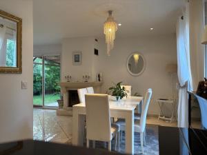 a dining room with a table and white chairs at belle maison 3000 m de Paris in Cachan