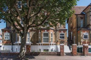 a large brick house with a tree in front of it at Folkestone Apartments in Folkestone