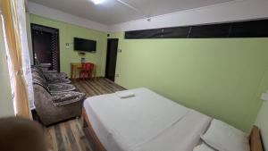 a room with a bed and a couch and a tv at Mebaker View Inn in Shillong