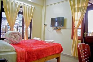 a bedroom with a bed with a red blanket and a tv at Mebaker View Inn in Shillong