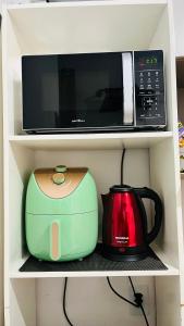 a microwave and a toaster sitting on a shelf at Kitnet com ar-condicionado e entrada privativa SC in Itajaí
