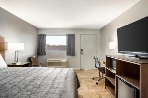 a hotel room with a bed and a flat screen tv at Home Inn & Suites in Orlando