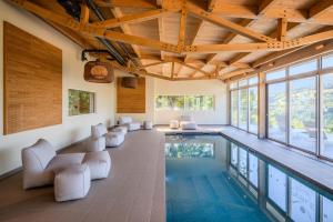 an indoor swimming pool with white chairs and a large ceiling at Logis Hôtel-Restaurant Perle Des Vosges in Muhlbach-sur-Munster