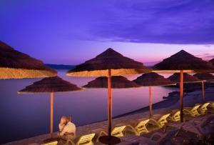 two people sitting on a beach with umbrellas at Easyatent Luxe Safari tent Krk in Krk