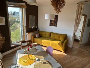 a living room with a yellow couch and a table at Rooms in an Apartment with Beautiful Views in Przemyśl