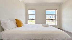 a bedroom with a large white bed with two windows at Westbrook 3B3B Home by GoodLive in Truganina