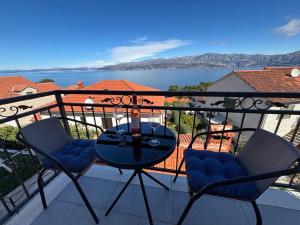 a balcony with a table and chairs and a view of the water at Apartman Bugenvila Postira Brač in Postira