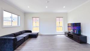a living room with a couch and a flat screen tv at Westbrook 3B3B Home by GoodLive in Truganina