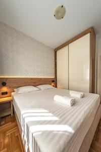 a bedroom with a large bed with two towels on it at Peace 2 Apartments with parking in Budva