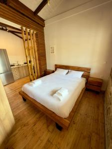 a bedroom with a large bed with white sheets and wooden floors at Eleon apartments in Kalamata