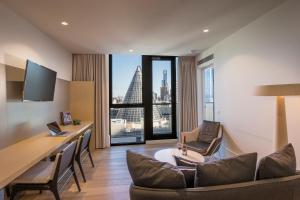 a hotel room with a desk and chairs and a large window at Brady Hotels Central Melbourne in Melbourne