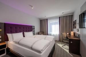 a bedroom with a large bed with a purple headboard at Premier Inn Hannover City Centre in Hannover
