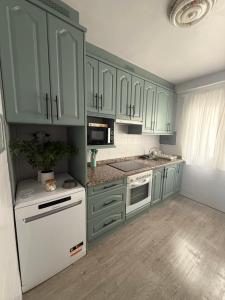 a kitchen with green cabinets and a white refrigerator at Amplio piso para 8 a 2 min de Playa Santa Marina, 3 habitaciones in Ribadesella