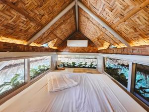 a bed in the back of a tiny house with windows at Teresito Dragon Fruit Farm in Bantayan Island
