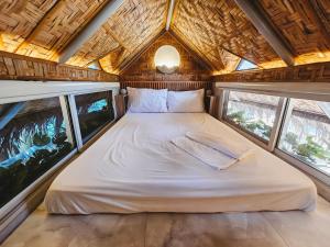 a bed in the middle of a room with windows at Teresito Dragon Fruit Farm in Bantayan Island +3 photos