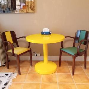 a yellow table with two chairs and a box on top at LE MASSITROU - chambre d'hôte - Table d'hôte in Nedde