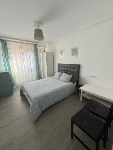 a bedroom with a bed and a table in it at Amplio piso para 8 a 2 min de Playa Santa Marina, 3 habitaciones in Ribadesella +7 photos