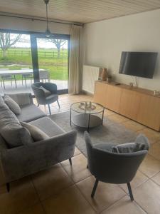 a living room with a couch and chairs and a tv at De Reynaarthoeve in Assenede