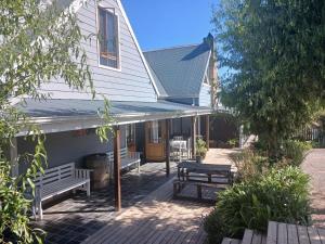 a white house with benches and a picnic table at Gables B&B Guesthouse in George