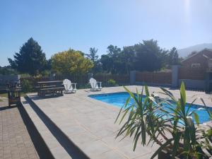 a swimming pool with chairs and a table and a bench at Gables B&B Guesthouse in George