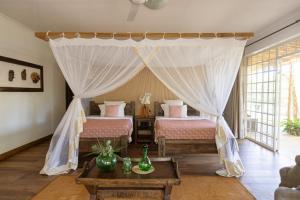 a bedroom with two beds and a canopy at Olerai Lodge in Arusha +51 photos
