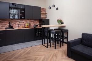 a kitchen with black cabinets and a table with stools at Apartament Podchorążych Dęblin in Dęblin +5 photos