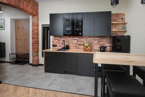 a kitchen with black cabinets and a brick wall at Apartament Podchorążych Dęblin in Dęblin