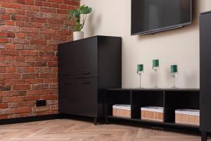 a black cabinet against a brick wall with a tv at Apartament Podchorążych Dęblin in Dęblin