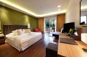 a bedroom with a bed and a desk with a television at Royal Paradise Beach Resort & Spa in Potos
