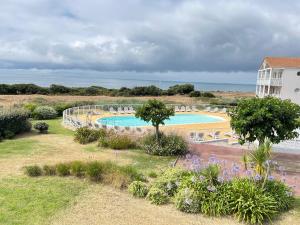 a swimming pool with chairs and the ocean in the background at Appartements front de mer 2 piscine chauffées la pironnière Residence de l'estrand in Les Sables-d'Olonne