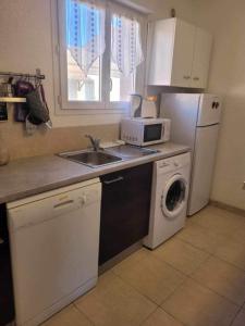 a kitchen with a sink and a washing machine at Maison à proximité de la plage in Prunete