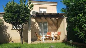 a patio with two chairs and a table in front of a house at Maison à proximité de la plage in Prunete