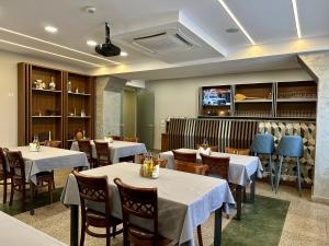 a dining room with tables and chairs and a tv at Lira Pacific Aparthotel in Constanţa