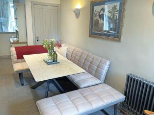 a living room with a table and a bench with flowers on it at Jasmine Cottage in Grassington