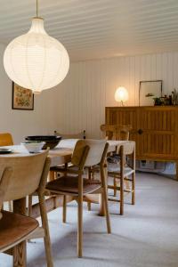 a dining room with a table and chairs and a light fixture at Thatched Hideaway At Svinkløv Forest Edge in Fjerritslev +26 photos