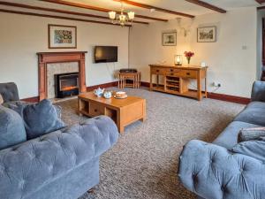 a living room with two blue couches and a fireplace at Whortleberry Cottage in Wheddon Cross